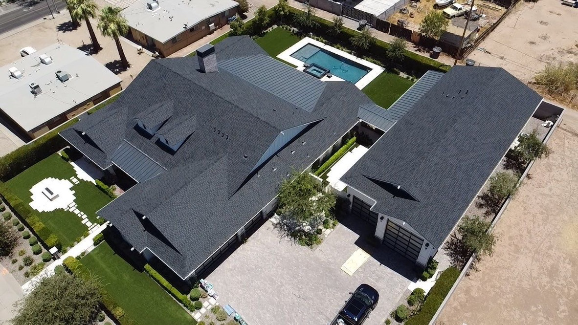 Aerial view of a finished Arizona residence with dark roofing and artificial turf
