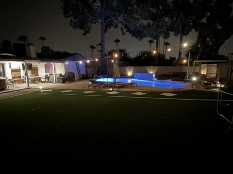 Artificial turf surrounding a pool and outdoor living area at night